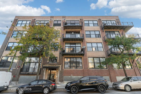 Front view of a multi-story brick apartment building with balconies.