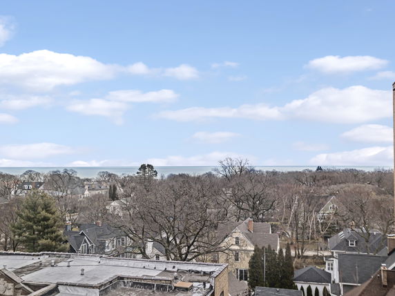 Wide angle view of a residential area with multiple houses and trees under a blue sky.