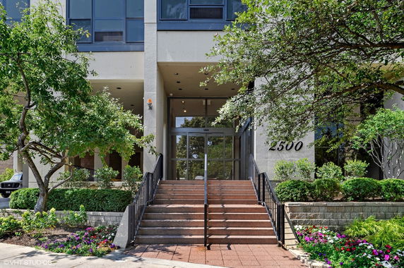 Front view of a multi-story building with large windows and stairs leading to the entrance.