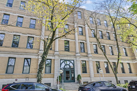 Front view of a multi-story building with arched entrance and large windows.