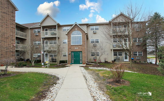 Front view of a three-story residential building with brick and siding exterior.
