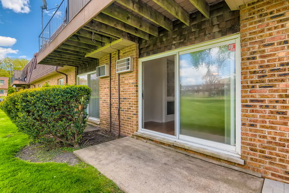 Exterior view of a brick building with sliding glass doors and balcony.
