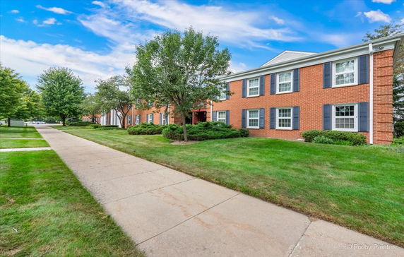 Front view of a two-story brick residential building with multiple windows and a landscaped pathway.