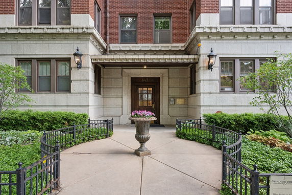 Front view of a multi-story building with brick and stone facade, featuring a main entrance and pathway.