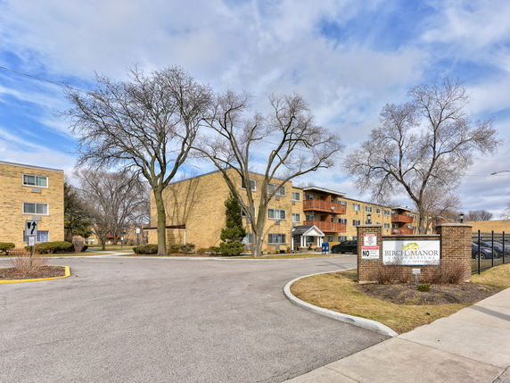 Front view of a residential condominium complex with multiple stories and a driveway.