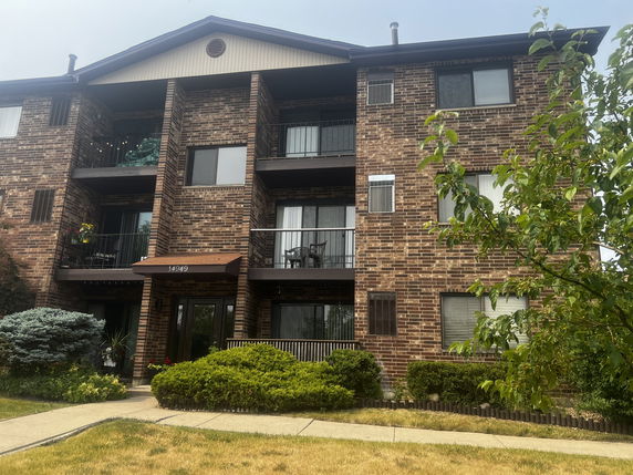 Front view of a multi-story brick apartment building with balconies.
