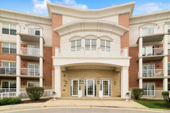 Front view of a multi-story building with balconies and an entrance with glass doors.