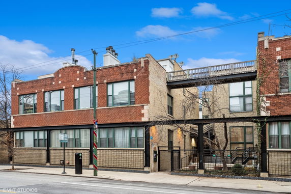 Front view of a two-story brick building with large windows and a connecting walkway.