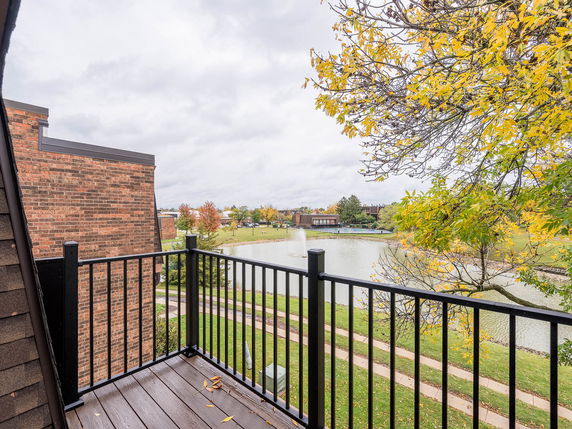 Balcony view overlooking a pond and surrounding greenery.