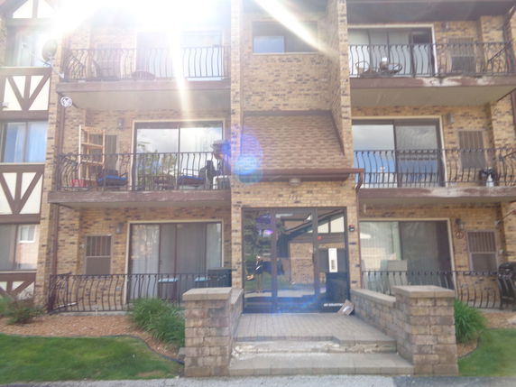Front view of a multi-story brick apartment building with balconies.