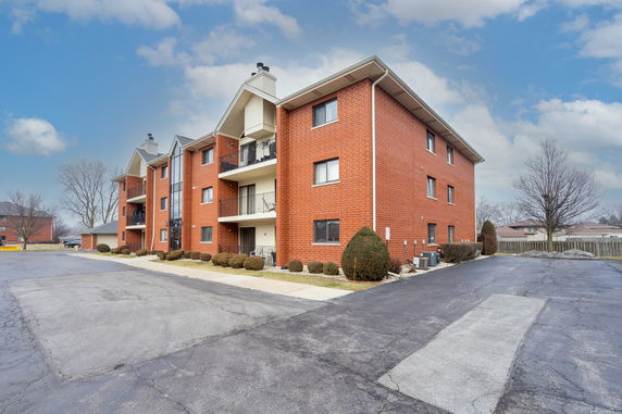 Front view of a multi-story brick apartment building with balconies.