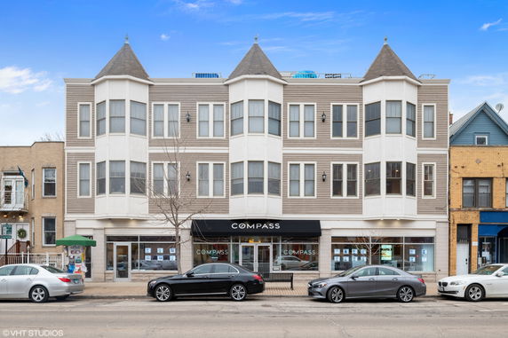Front view of a three-story commercial building with turrets and a retail space on the ground floor.