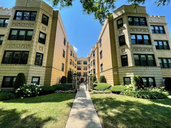 Front view of a multi-story apartment building with a walkway leading to the entrance.