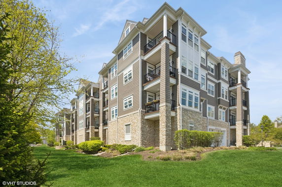 Front view of a multi-story residential building with balconies and stone facade.