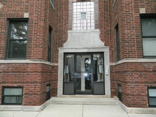 Front view of a brick building entrance with double glass doors.