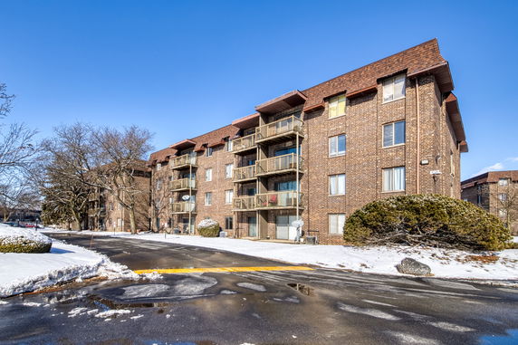 Front view of a multi-story brick apartment building with balconies.