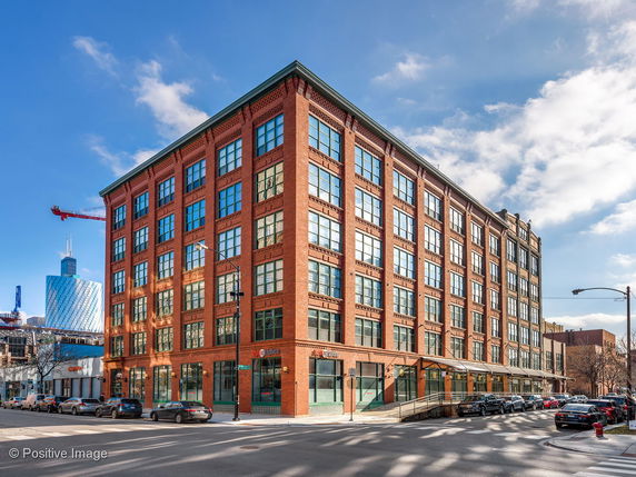 Front view of a multi-story brick building on a street corner.