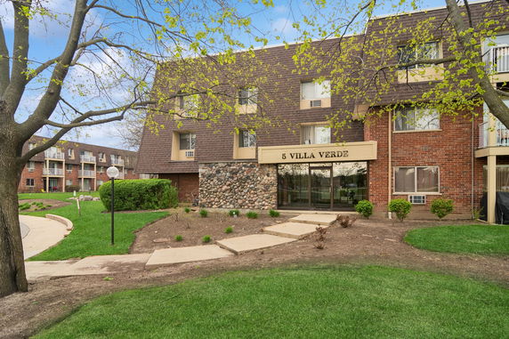 Front view of a multi-story brick apartment building with a sloped roof.