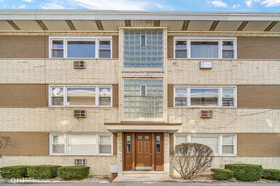 Front view of a three-story apartment building with a central entrance and multiple windows.