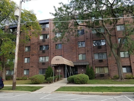 Front view of a multi-story brick apartment building with an entrance canopy.
