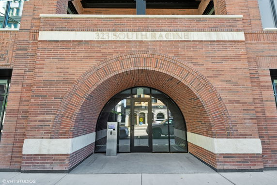 Front view of a brick building with an archway entrance and glass doors.