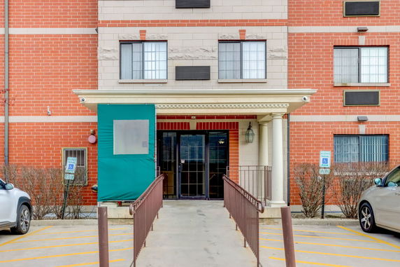 Front view of a multi-story brick building entrance with a ramp.