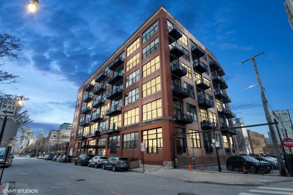 Front view of a multi-story brick building with large windows and balconies.