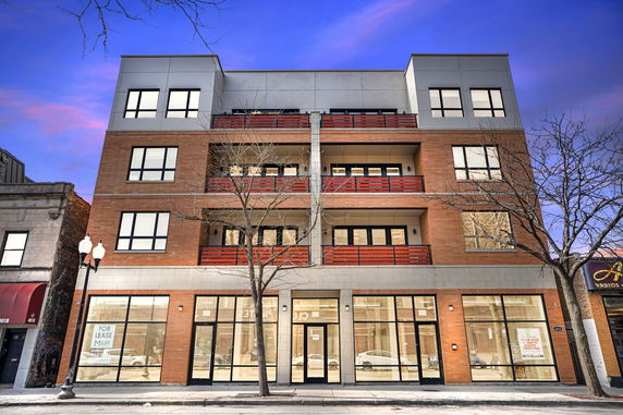 Front view of a modern multi-story building with large windows and balconies.