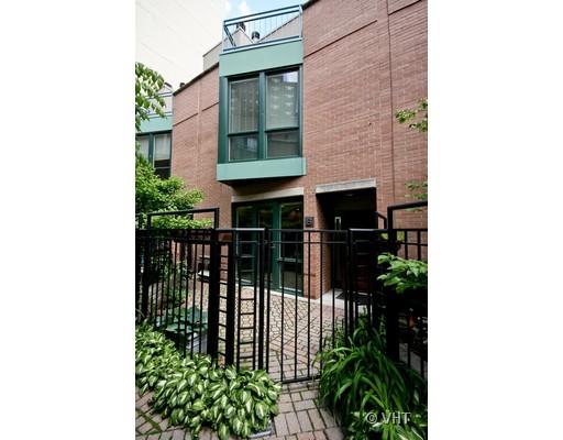 Front view of a two-story brick house with green window frames and a gated entrance.