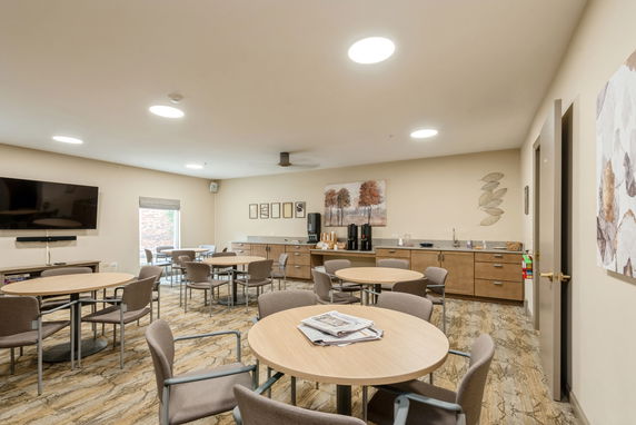 Indoor recreation area with tables, chairs, a TV, and a refreshment counter.
