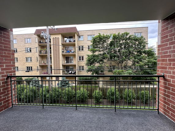 View from a balcony overlooking an apartment building and greenery.
