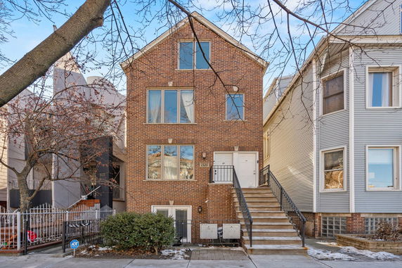 Front view of a multi-story brick house with a staircase leading to the entrance.