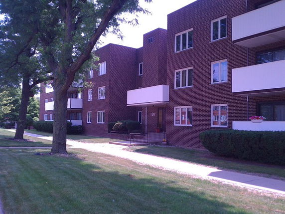 Front view of a multi-story brick apartment building with balconies.