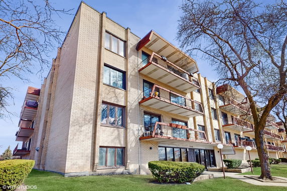 Front view of a multi-story building with balconies and brick facade.