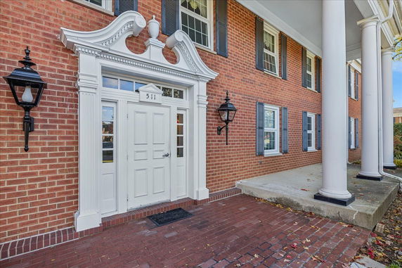 Front view of a brick building with white columns and decorative door frame.