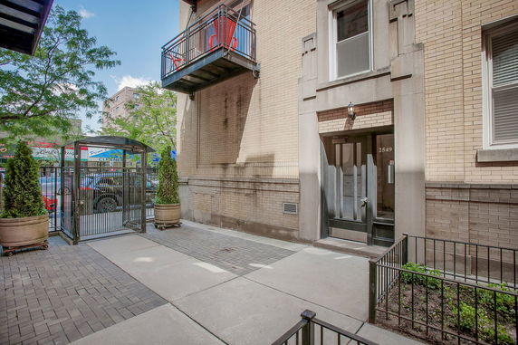 Front view of a building entrance with a metal gate and brick exterior.