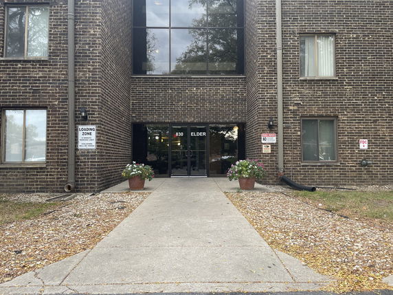 Front view of an apartment building with brick exterior and glass entrance.