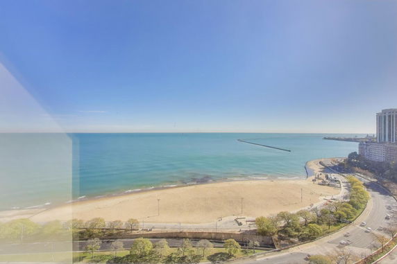 Panoramic view of a beach and oceanfront with nearby roads and buildings.