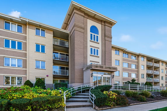 Front view of a multi-story apartment building with balconies and an arched window feature.