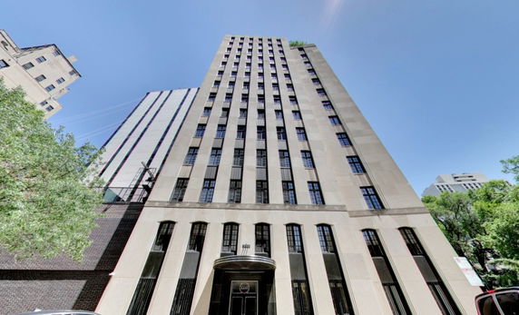 Front view of a multi-story building with numerous windows against a clear blue sky.