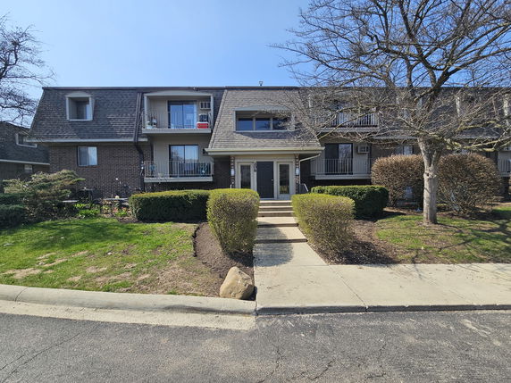 Front view of a two-story residential building with balconies and a central entrance.
