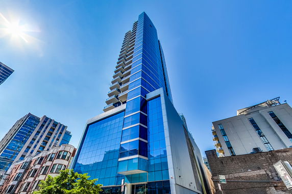Front view of a tall modern skyscraper with a blue glass facade