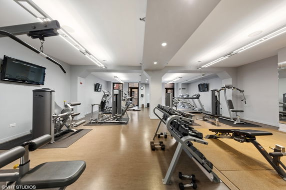 Interior view of a gym area with exercise equipment and weights.