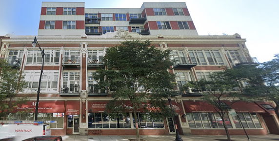 Front view of a multi-story building with large windows and balconies.