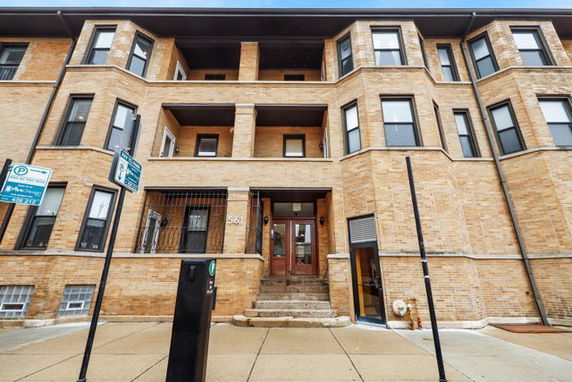 Front view of a multi-story brick building with numerous windows and entry steps.