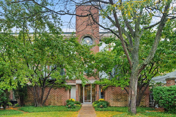 Front view of a two-story brick building with a central chimney.