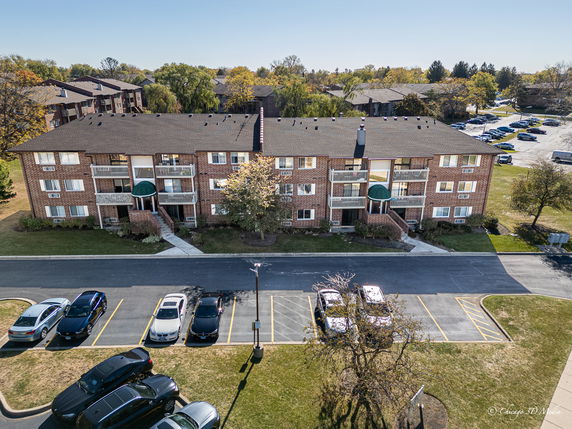 Front view of a three-story brick apartment building with balconies.