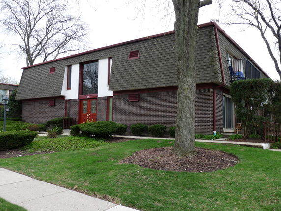Front view of a two-story building with a sloped roof and brick exterior.
