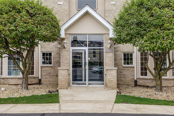 Front view of a multi-story brick building entrance with a glass door.