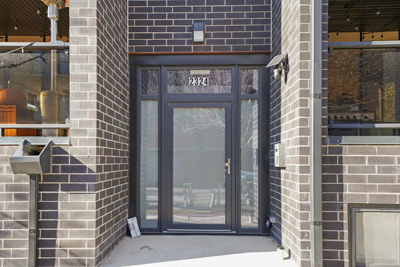 Front entrance of a building with a glass door and brick facade.